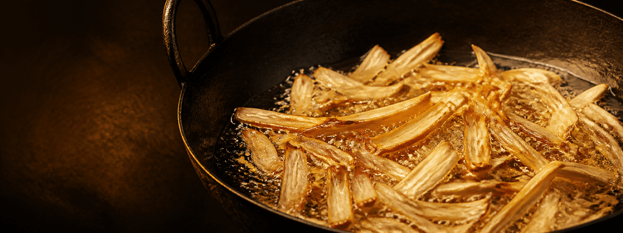 Thin jackfruit strips frying in bubbling coconut oil
